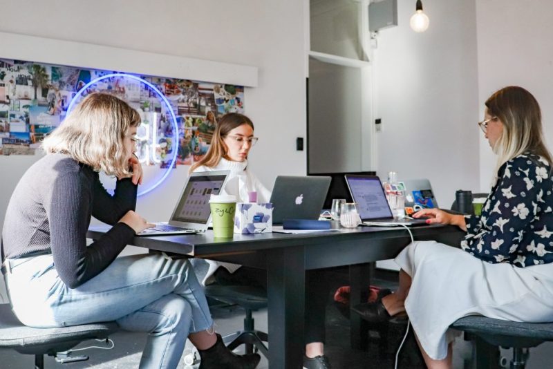 three women sitting at table with laptops; performance marketing agency